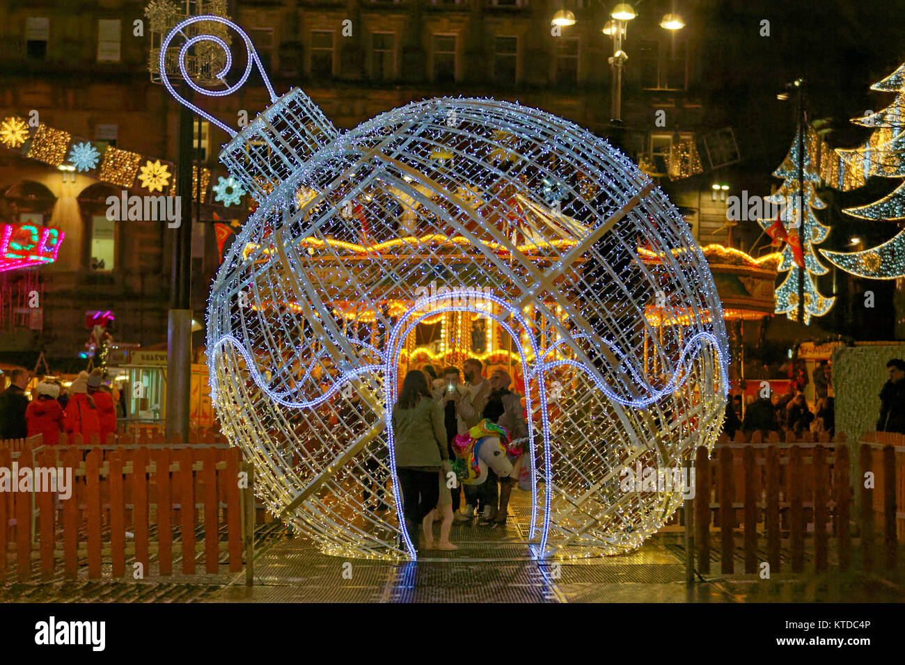 Rain and wind greet the last minute Christmas Eve visitors to the Christmas fayre in the city’s George square. tourists take selfies inside ornament Stock Photo