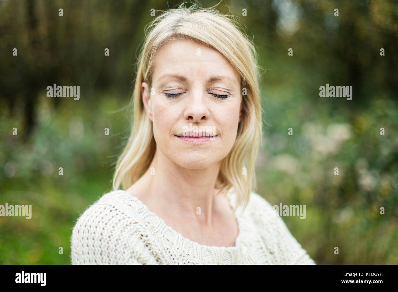 Portrait of blond woman with eyes closed outdoors Stock Photo - Alamy