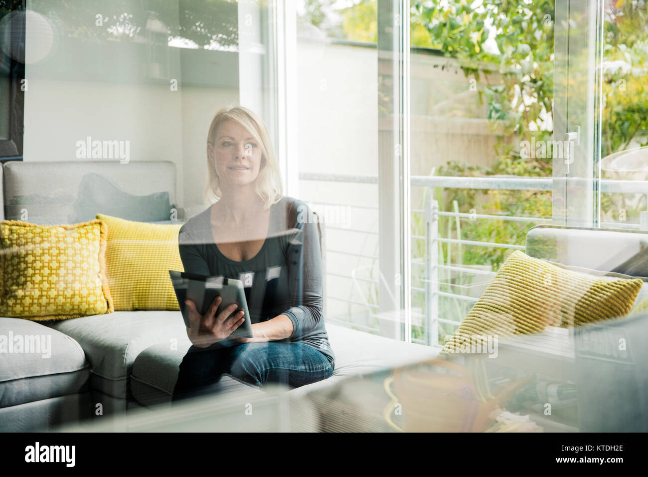 Woman holding tablet on couch Stock Photo - Alamy