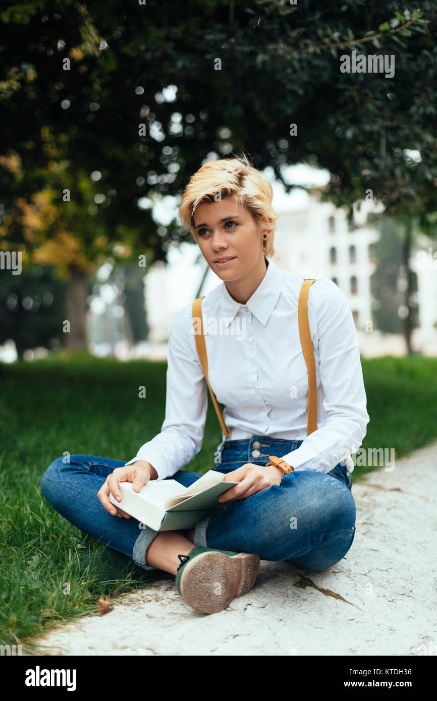 Teenage girl sitting cross legged in a park hi-res stock photography ...