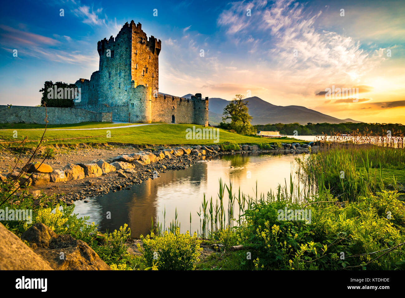 Ancient old Fortress Ross Castle ruin with lake and grass in Ireland during golden hour nobody Stock Photo