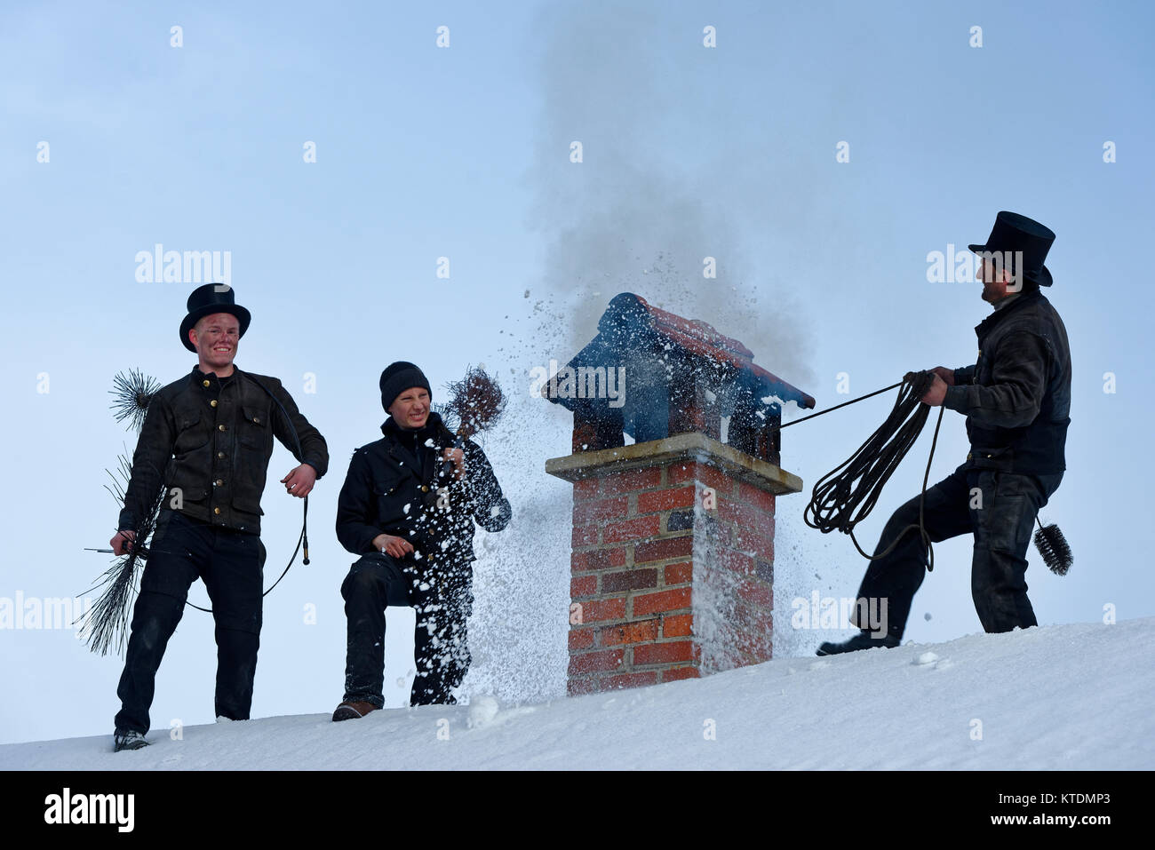 Schornsteinfeger, Kaminkehrer im Winter, auf einem Dach mit qualmenden Kamin, Schornstein, Bad Heilbrunn, Oberbayern, Bayern, Deutschland Stock Photo