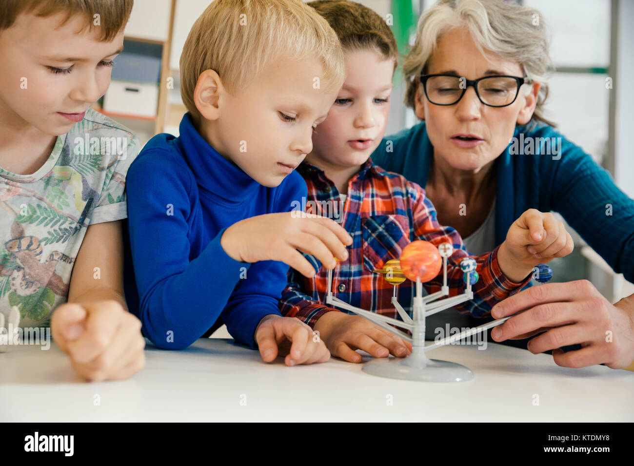 Pre-school teacher explaining solar system model to boys in kindergarten Stock Photo