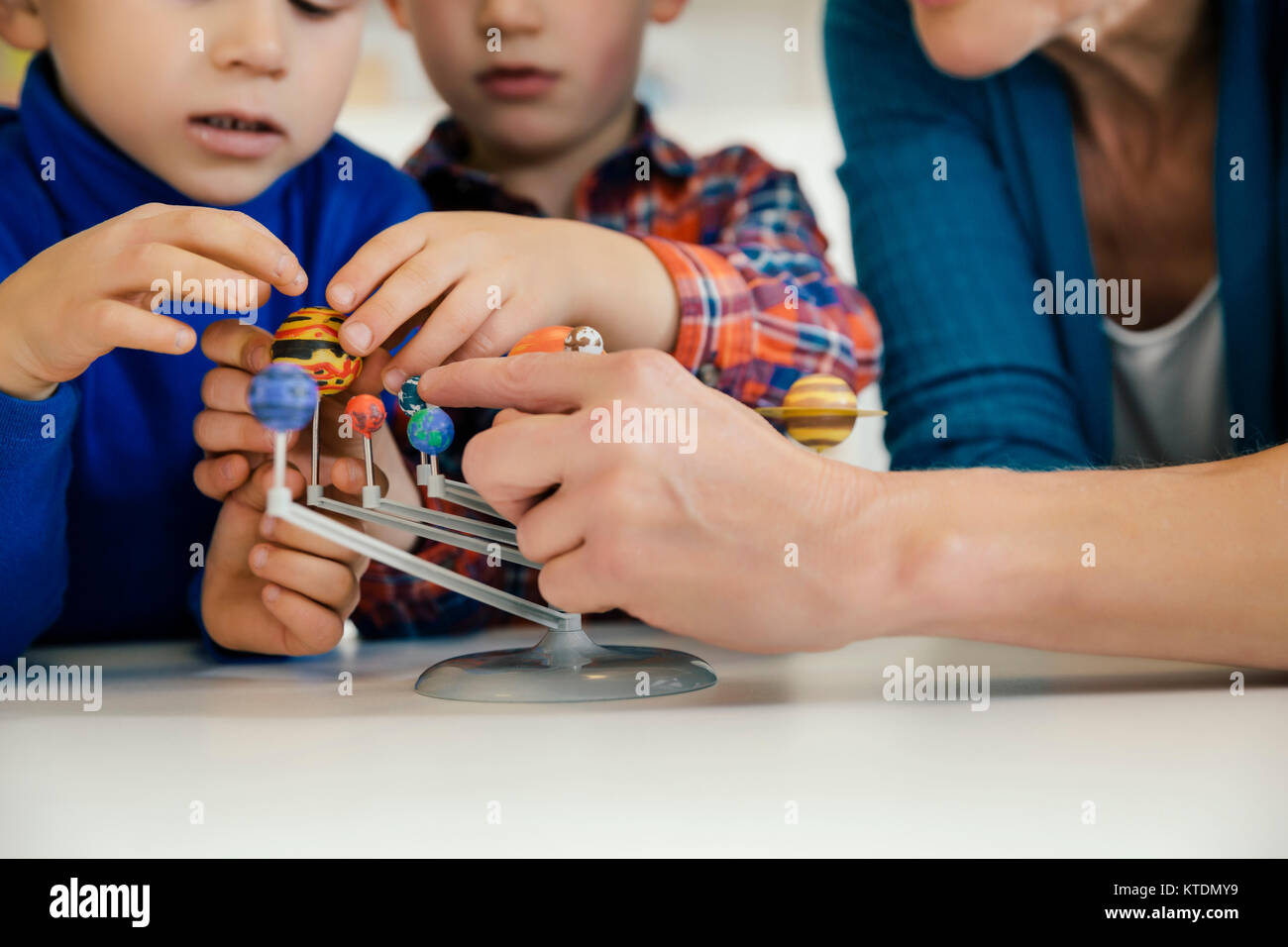 Pre-school teacher and boys exploring solar system model in kindergarten Stock Photo
