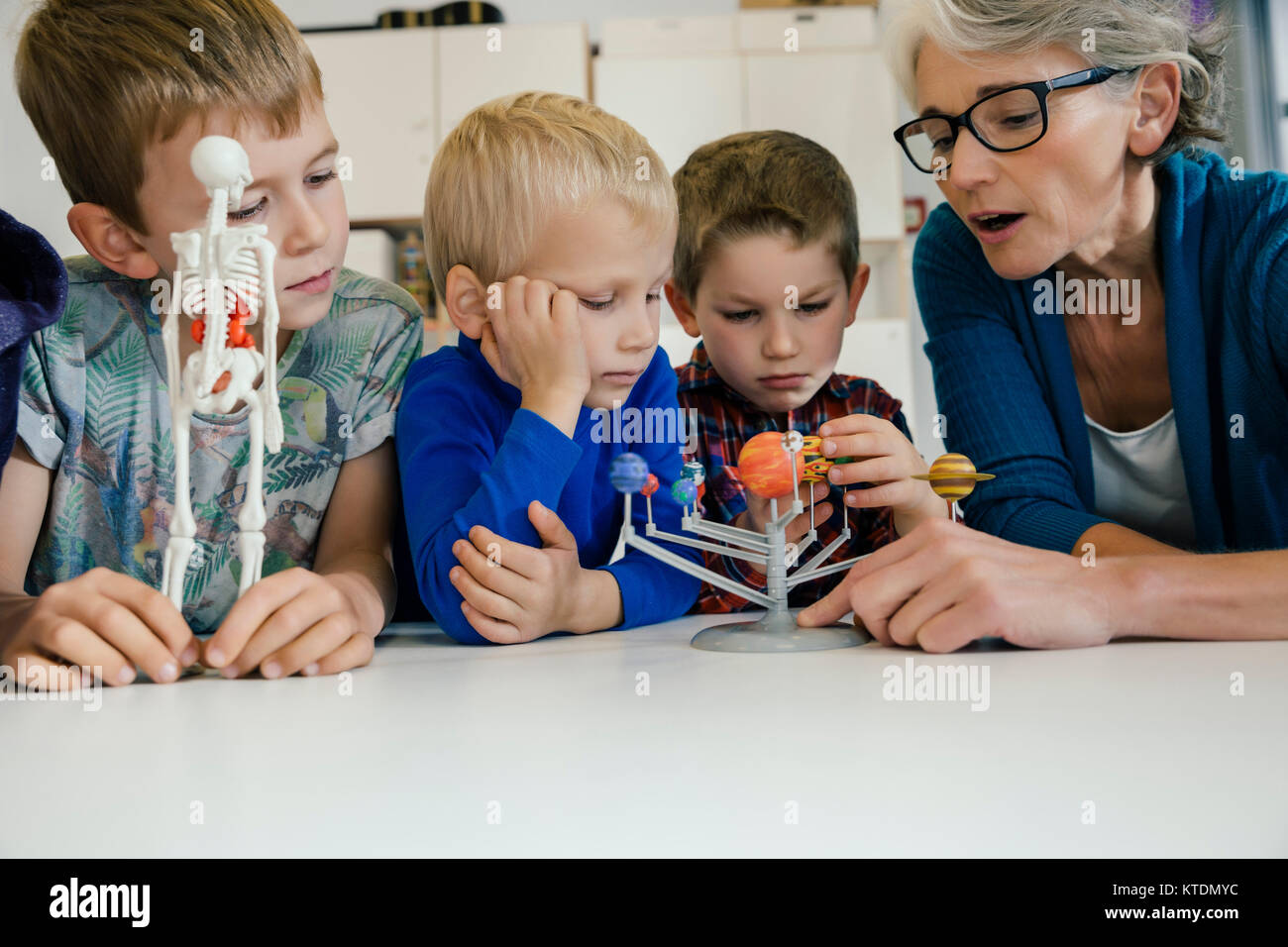 Pre-school teacher explaining solar system model to boys in kindergarten Stock Photo