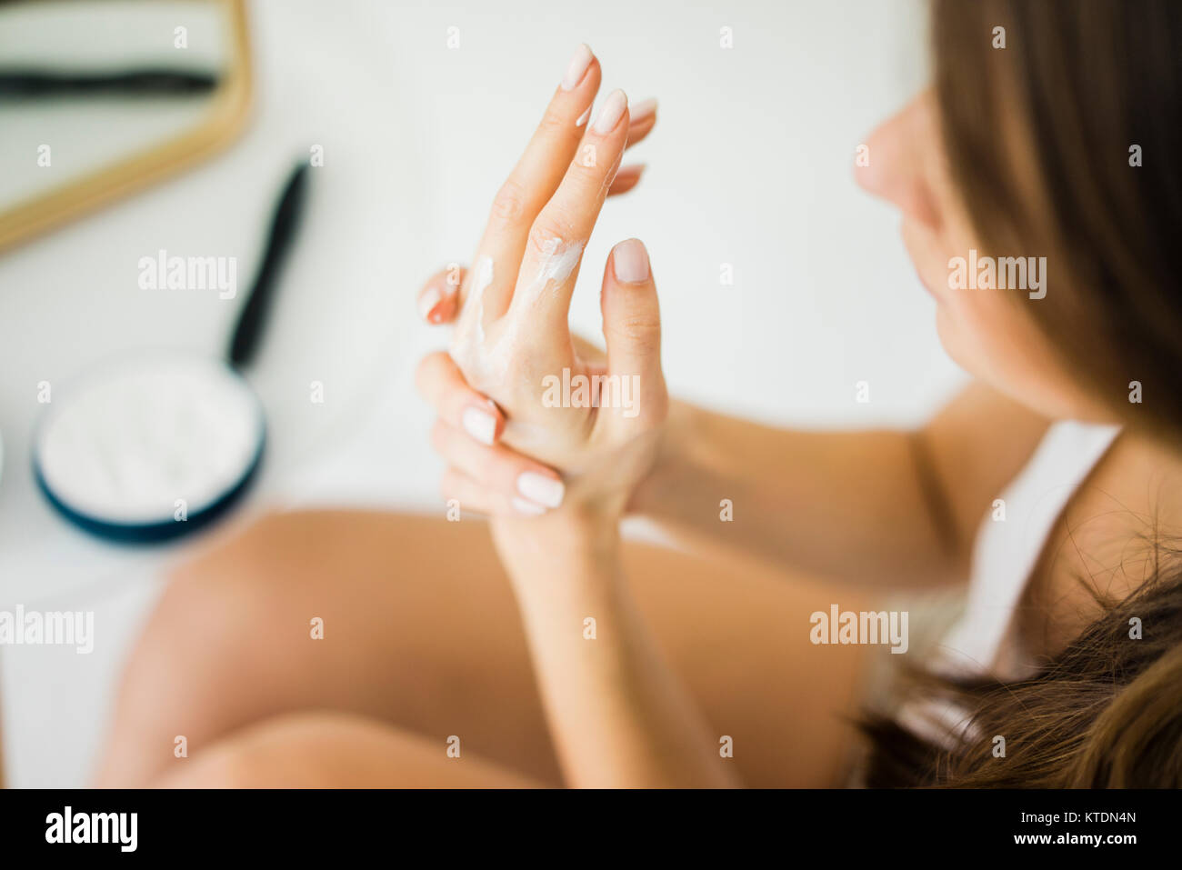 Woman creaming her hands, partial view Stock Photo