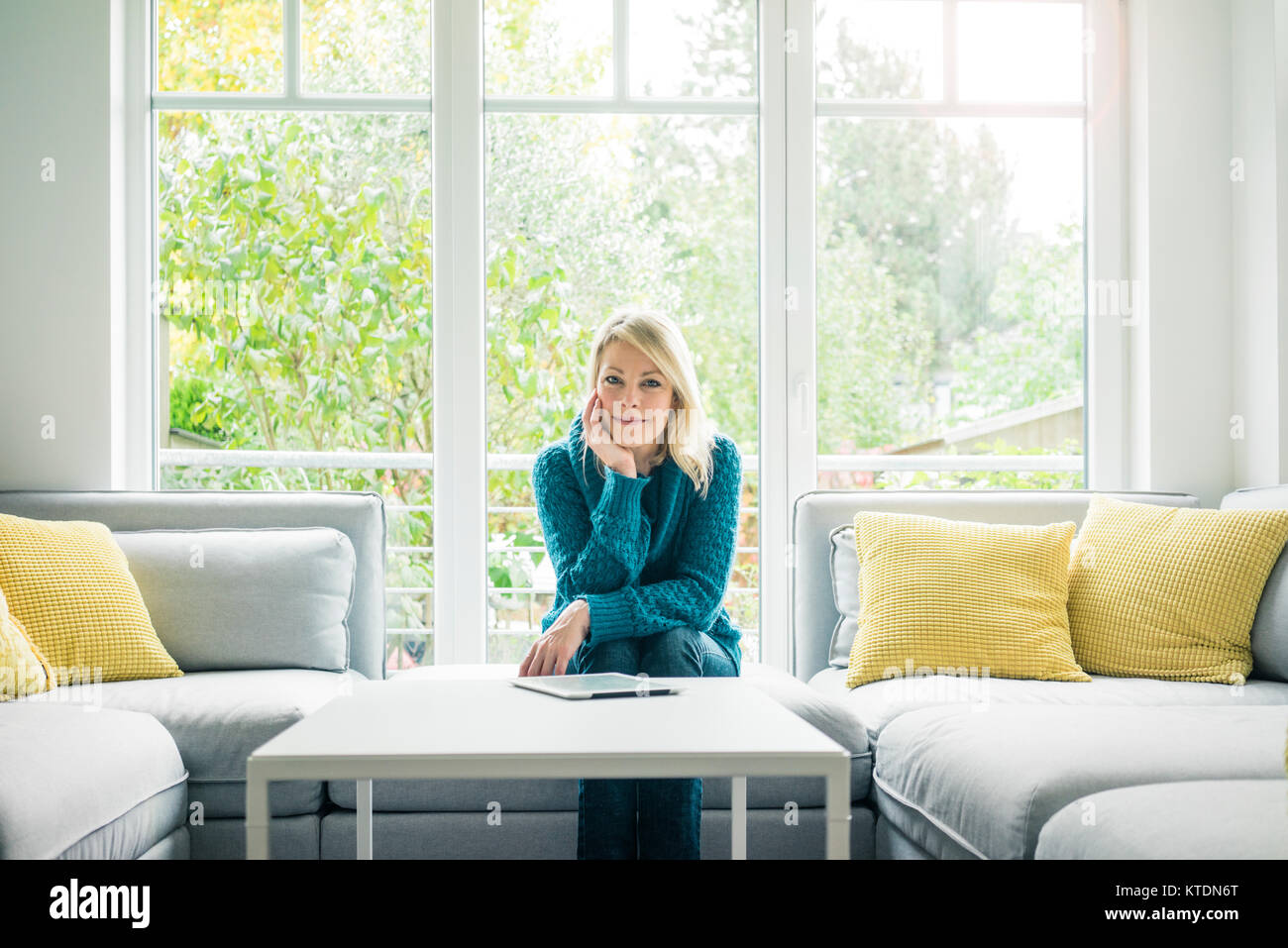 Portrait of smiling woman with tablet on couch Stock Photo - Alamy
