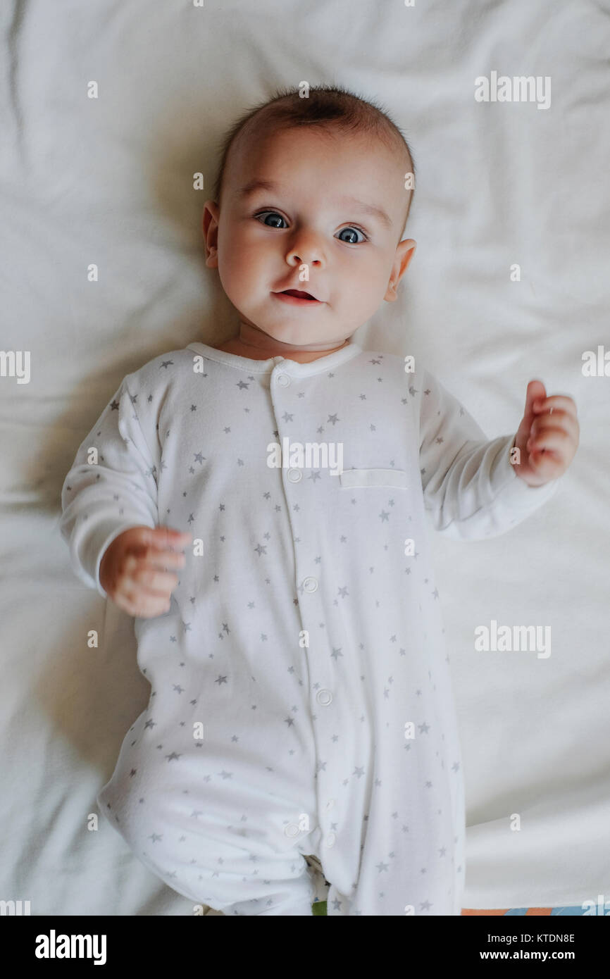 Portrait of baby boy wearing sleepers lying on bed Stock Photo Alamy