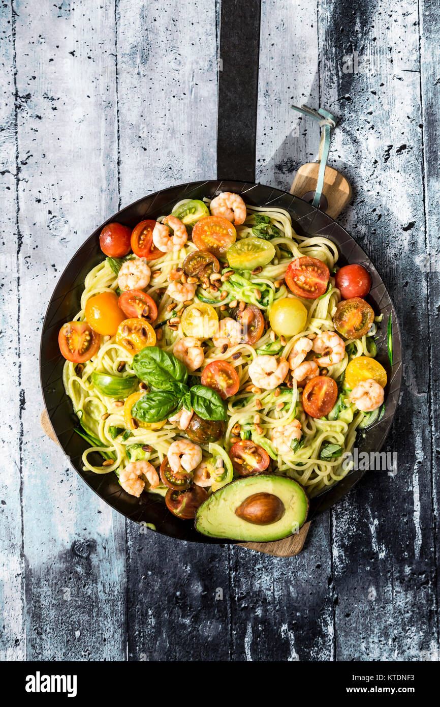 Frying pan of spaghetti with zoodles, guacamole, tomatoes and shrimps