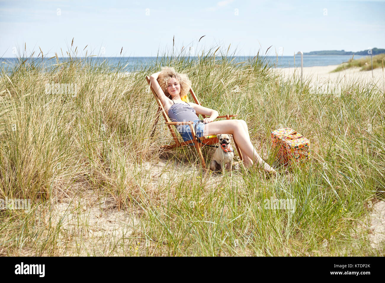 Happy young woman sitting on beach chair in the dunes Stock Photo - Alamy