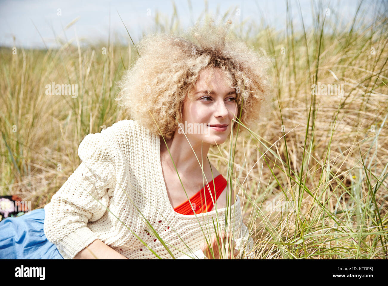 Portrait of smiling young woman relaxing in beach dunes Stock Photo - Alamy