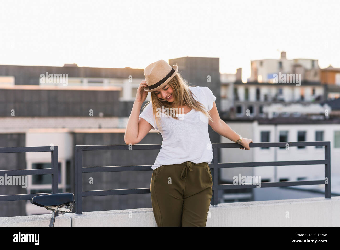 Smiling young woman leaning against railing in the city Stock Photo - Alamy