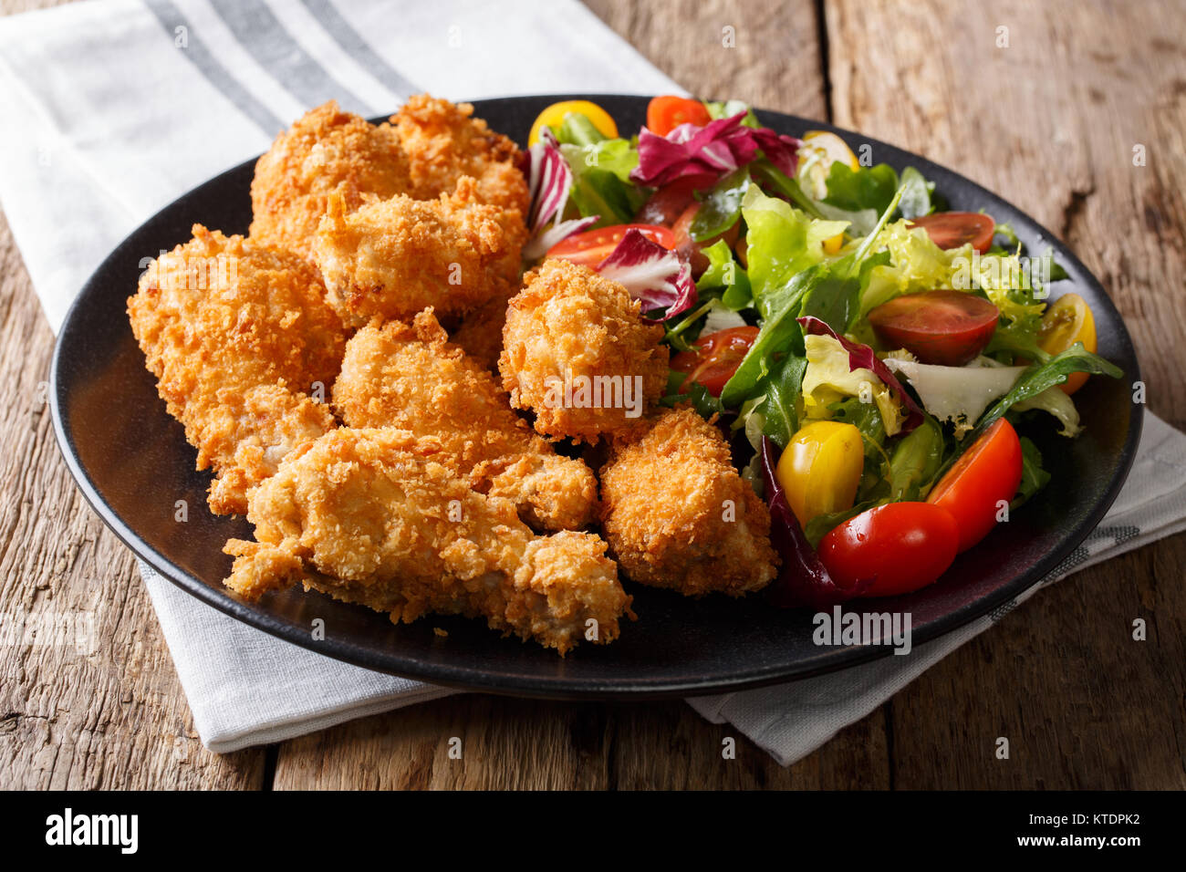 Fried chicken wings in breadcrumbs and fresh vegetable salad closeup