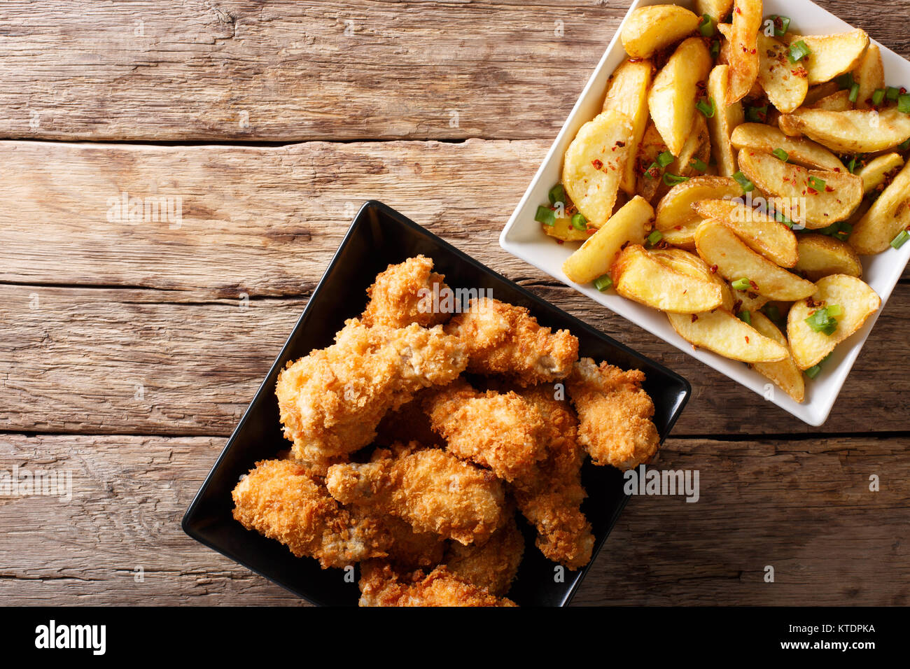 Fried chicken wings in bread crumbs and potato wedges close up on the