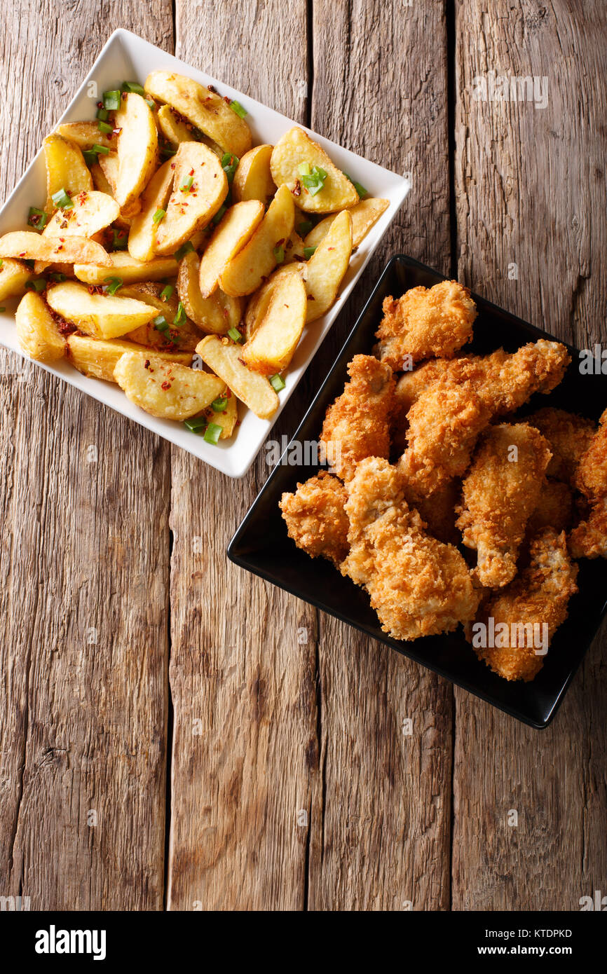 Fried chicken wings in bread crumbs and potato wedges close up on the