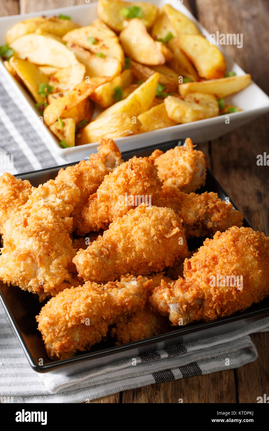 Fast food: fried chicken wings in breadcrumbs and potato close-up on the table. vertical Stock Photo
