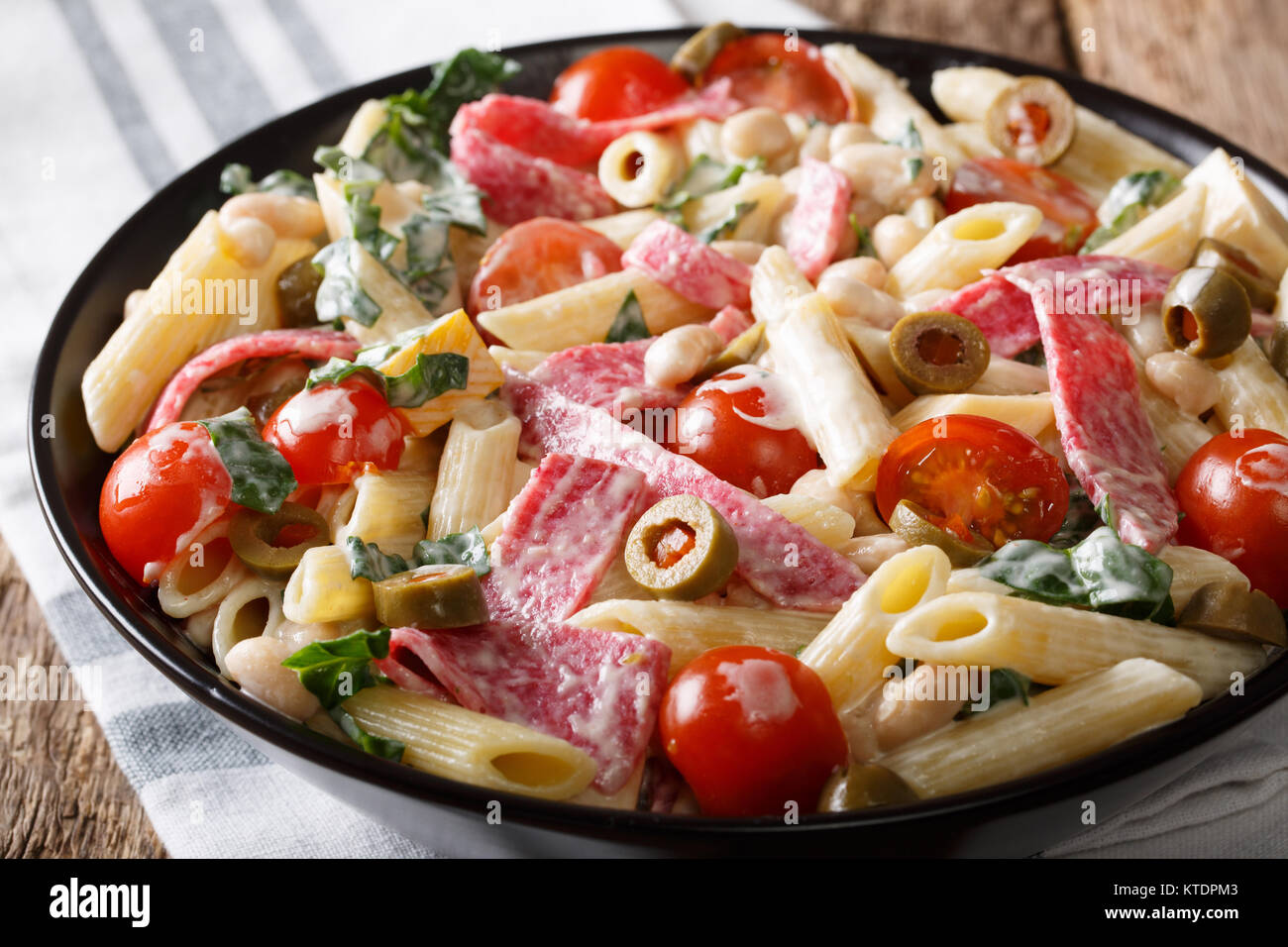 Delicious salad of pasta, salami, cheese, and vegetables with cream