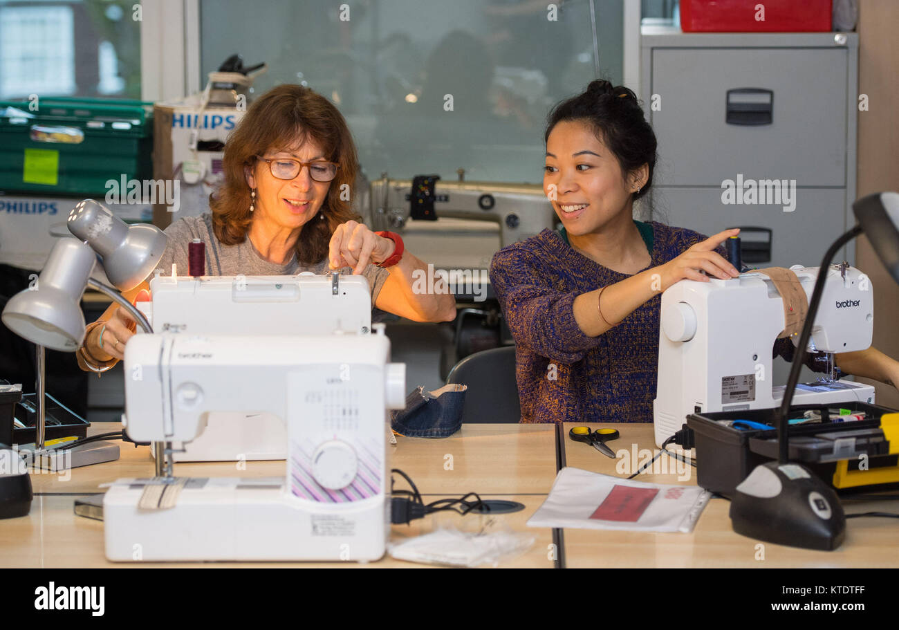 Crisis employees Maggie Chute (left) and Janet Law at work repairing items of clothing and other personal items at a Crisis at Christmas centre in north London. Stock Photo