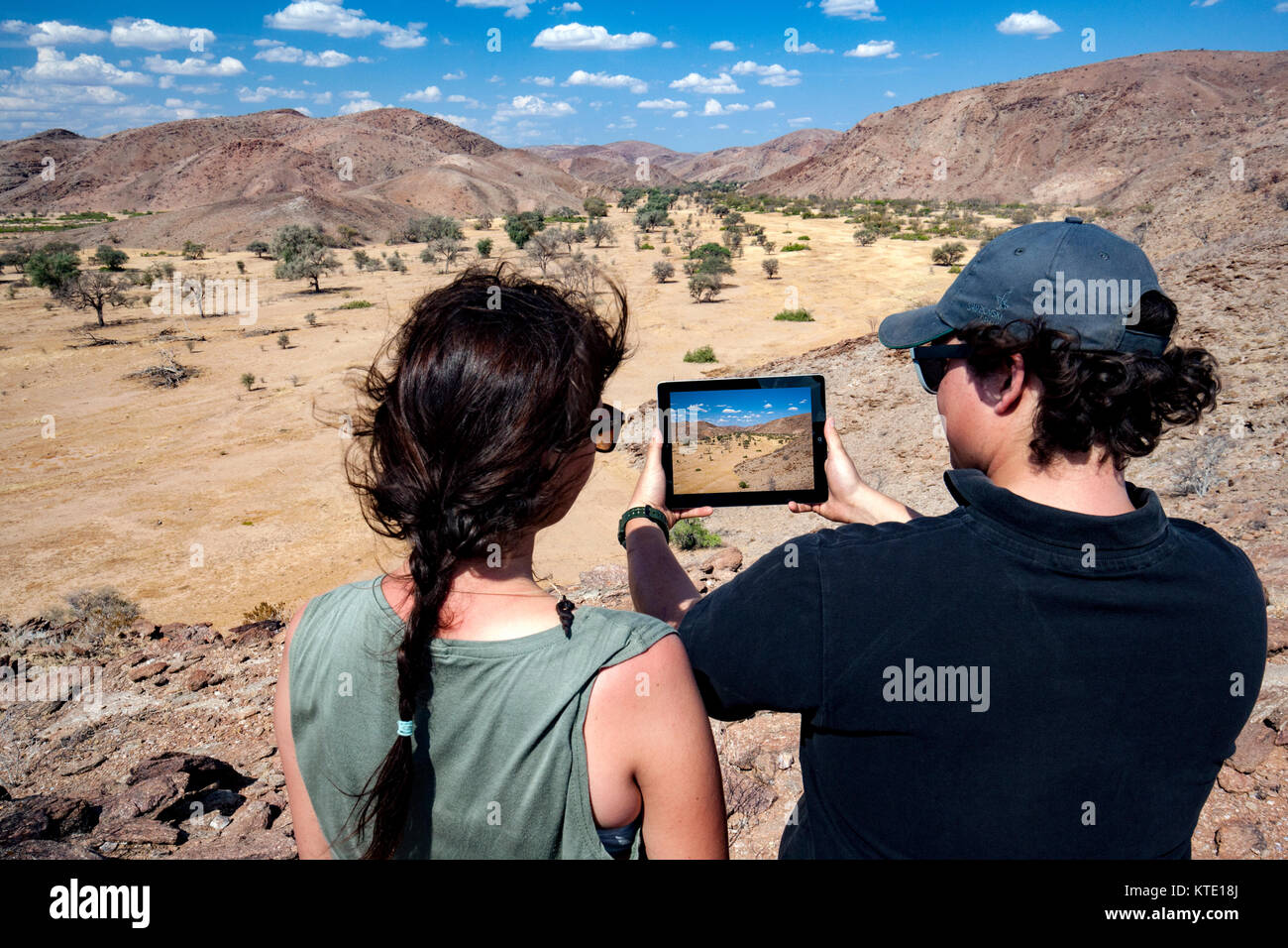 Couple taking picture with tablet in Damaraland - Huab Under Canvas, Damaraland, Namibia, Africa Stock Photo