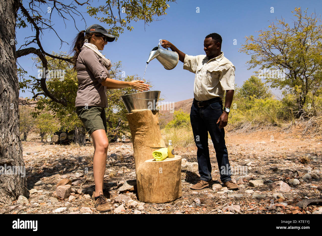 Woman washing her hands in tin basin - Huab Under Canvas, Damaraland, Namibia, Africa Stock Photo