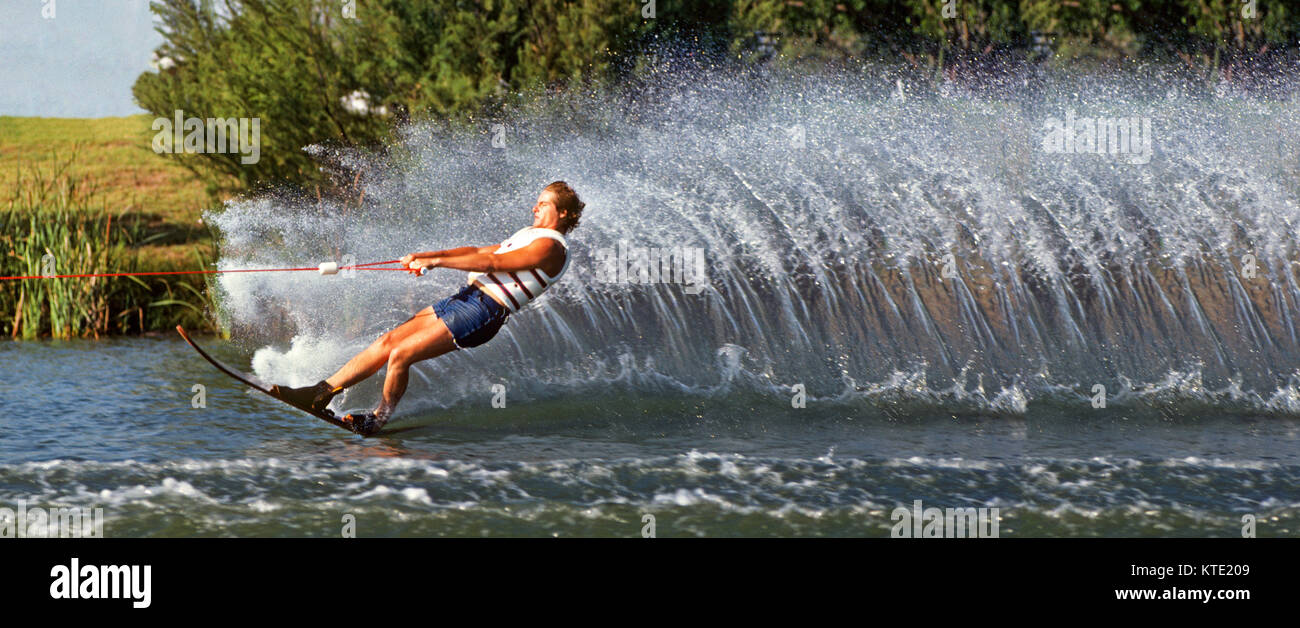 A slalom waterskiier creates a rooster tail as he skis along a river bank in western Oregon. Stock Photo