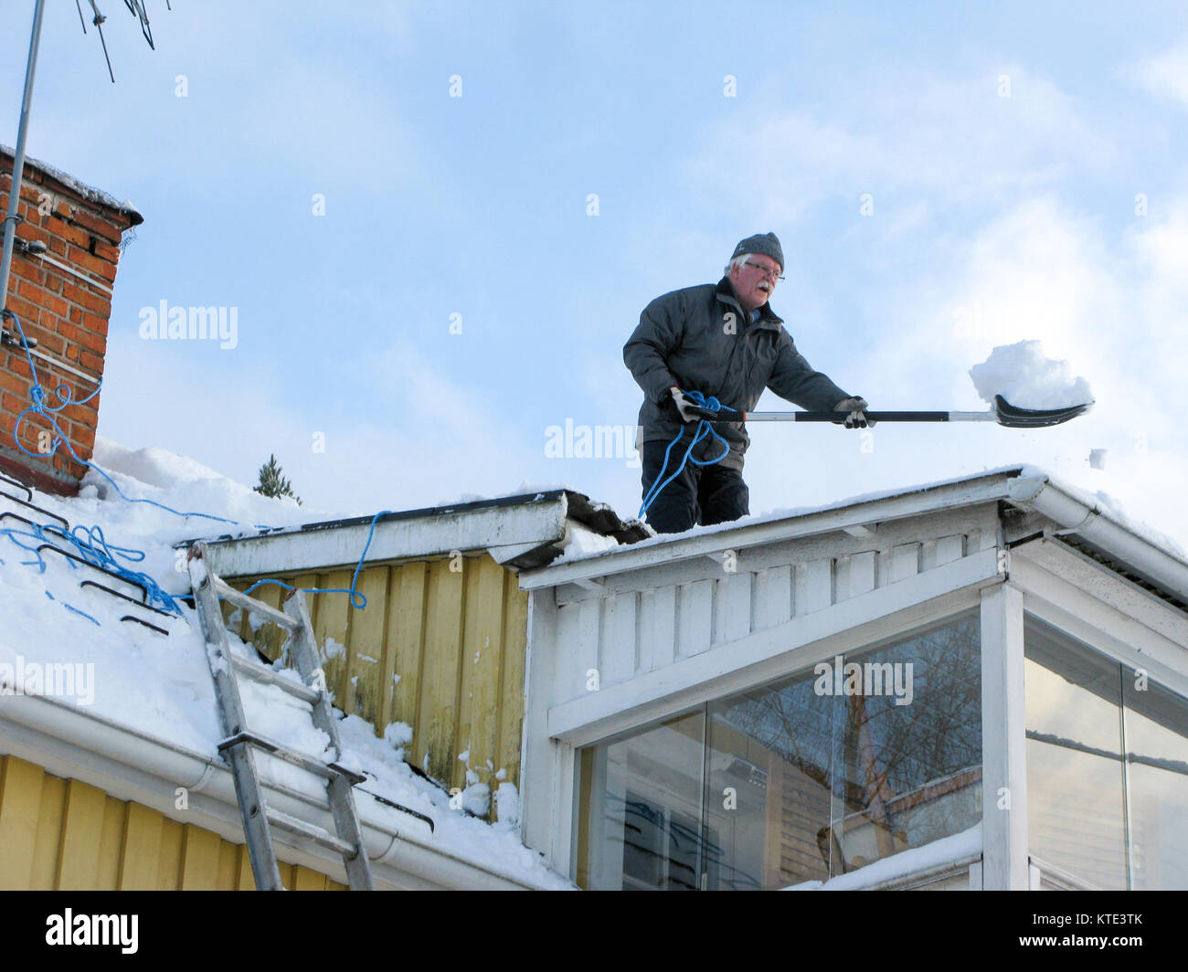 Shovling snow from roof of a house Stock Photo