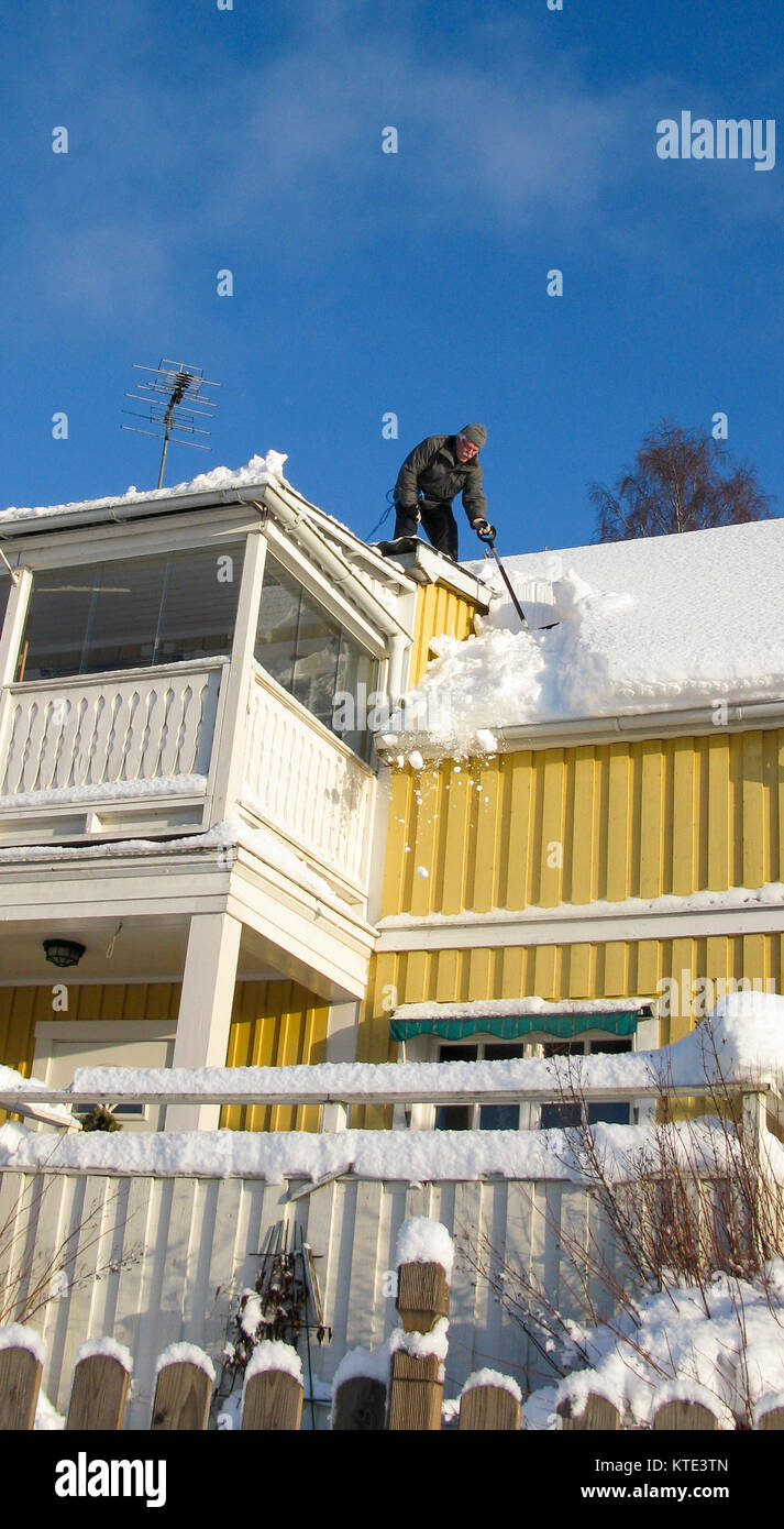 Shovling snow from roof of a house Stock Photo