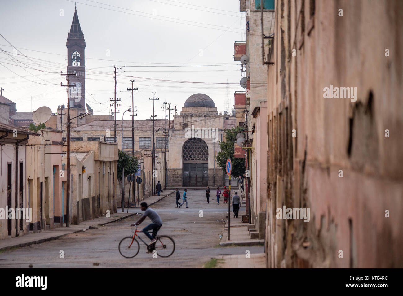 A man on a bicycle cross a street in the city of Asmara, Eritrea on the Horn of Africa. Stock Photo
