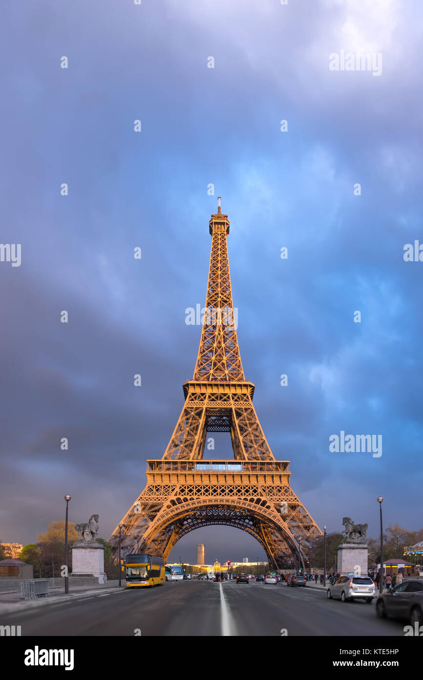 Eiffel Tower on a stormy evening with the last rays of setting Sun shining between the clouds. Panorama made from four horizontal images. Stock Photo