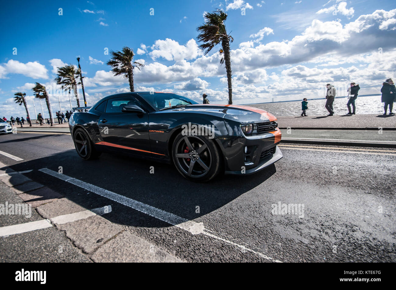 Chevrolet Camaro, American muscle car, Pony car driving along Southend on Sea seafront with palm trees and Thames Estuary on sunny day Stock Photo