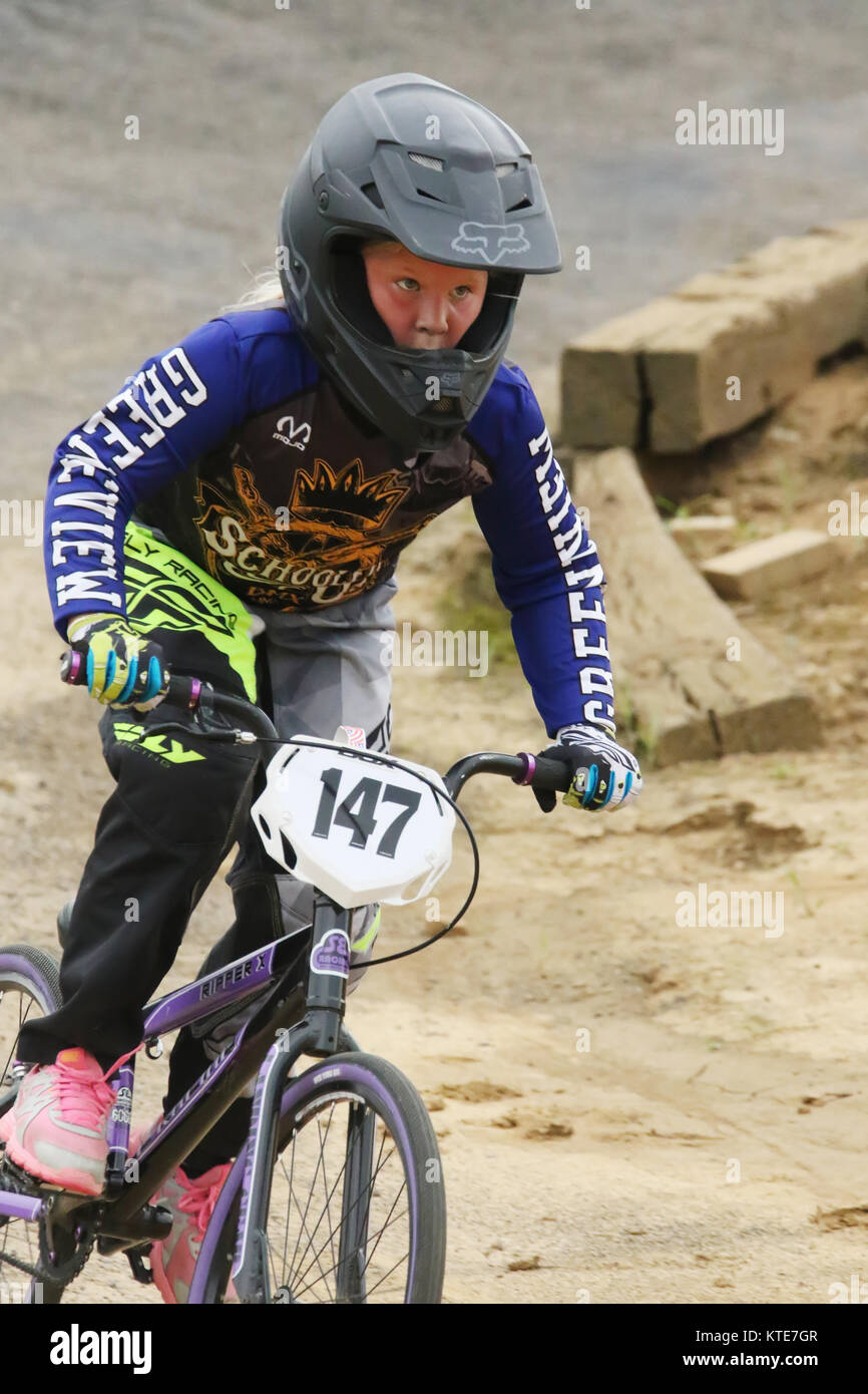 Young girl riding BMX bicycle. Riders at Kettering BMX race night. BMX Track, Delco Park, Kettering, Dayton, Ohio, USA. Stock Photo