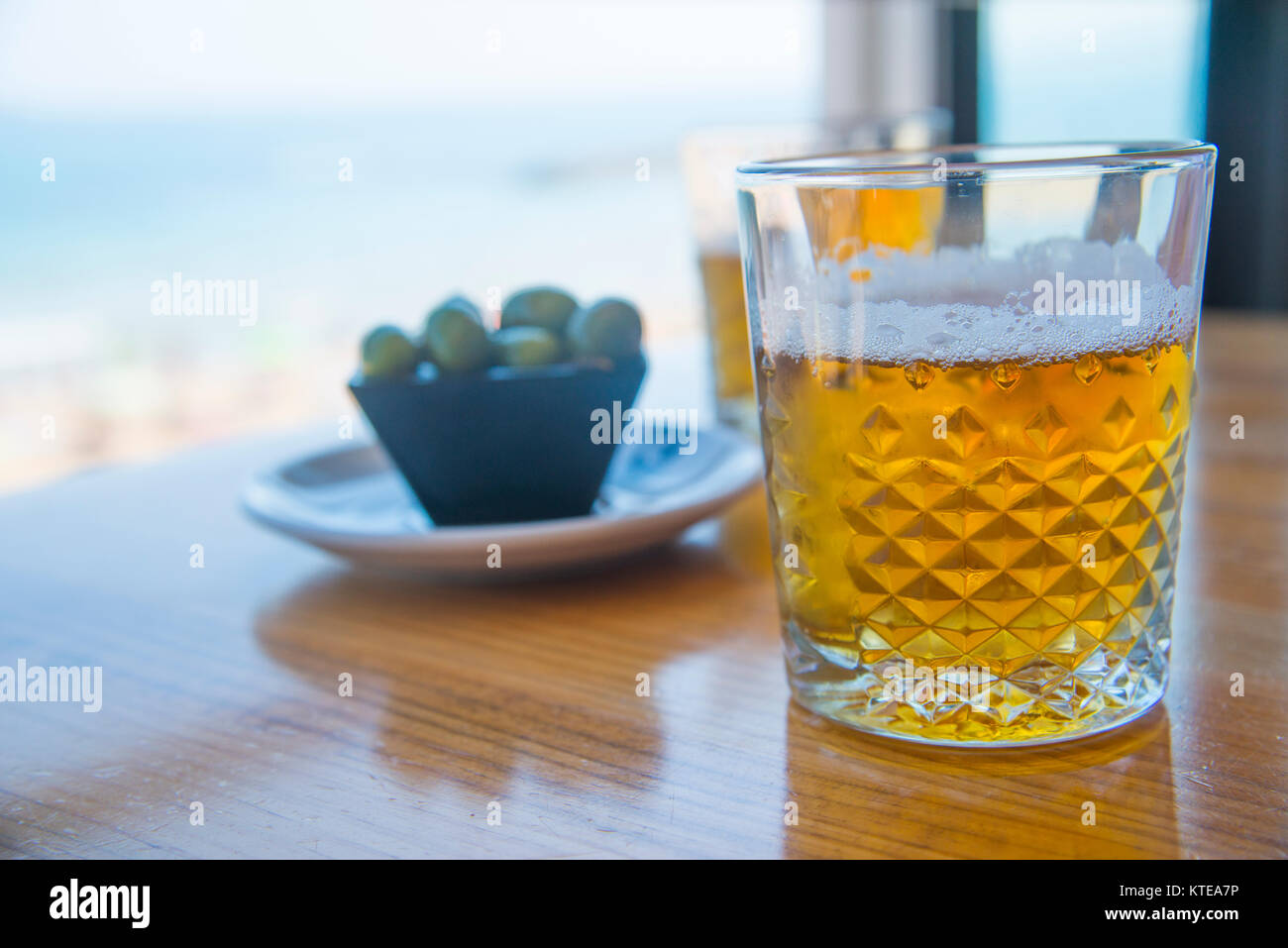 Two glasses of beer and tapa of green olives in the beach. Santander, Spain. Stock Photo