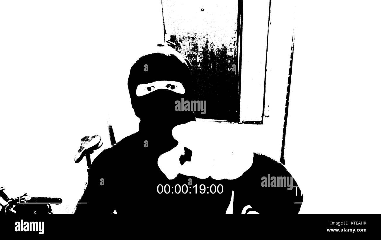 the masked robber burst through the door and threatened with a knife in CCTV camera threshold effect Stock Photo