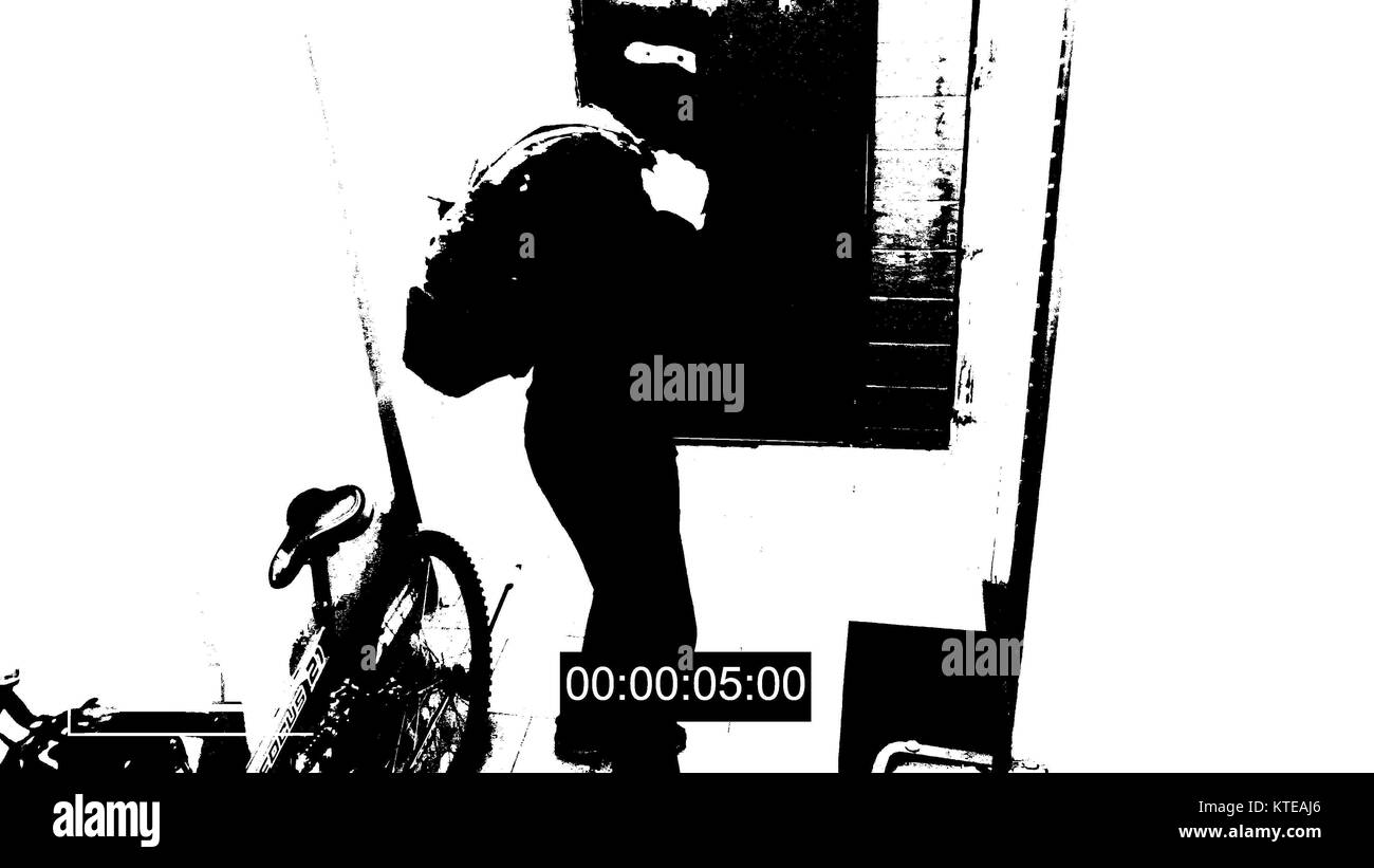surveillance camera caught the robber in a mask running off with a bag of loot,shows the camera the middle finger threshold effect Stock Photo