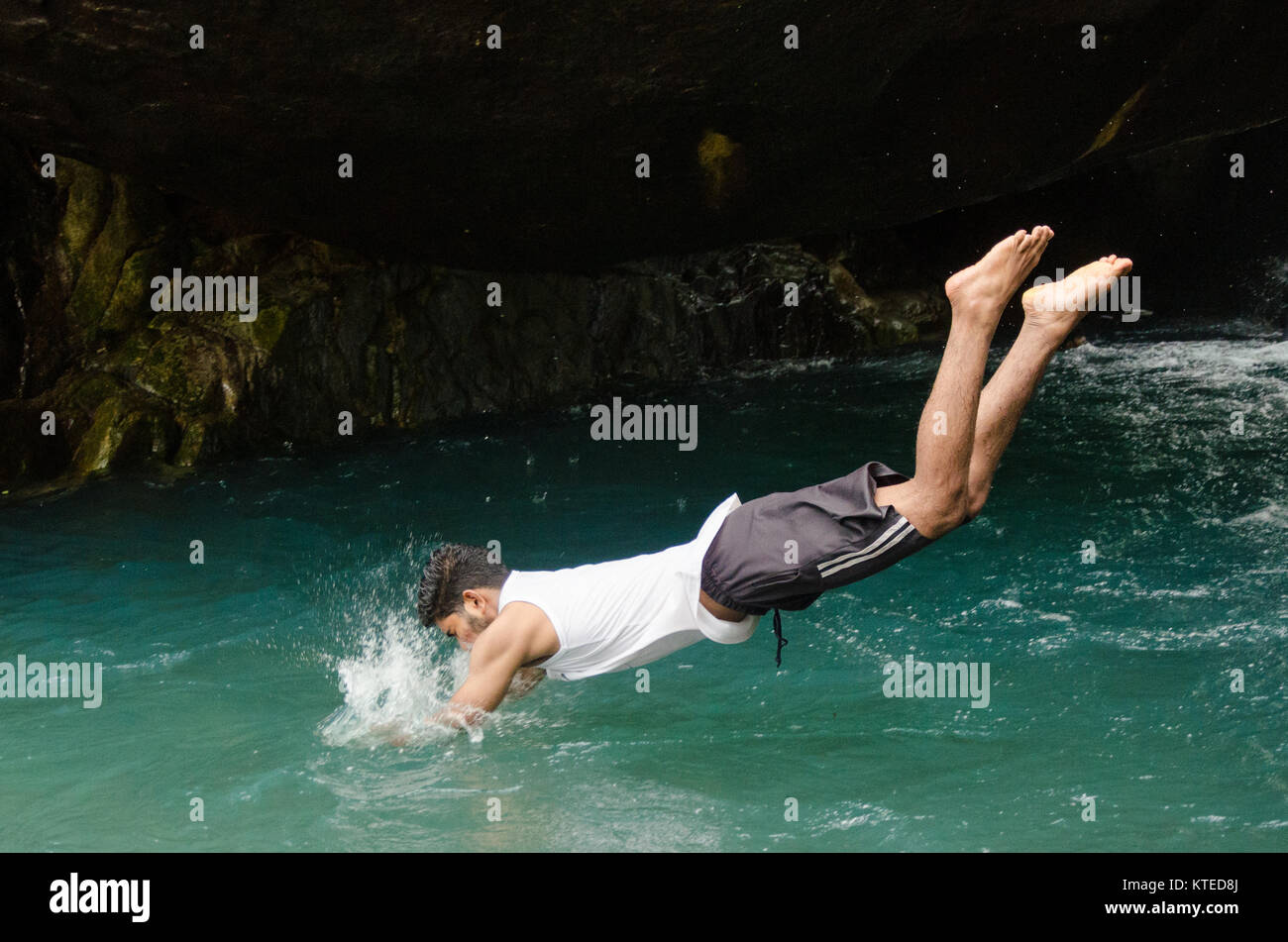 Boy diving head first into cool blue waters, creating a splash at Nagarmadi Water Falls, Chendia, Karnataka, India. Stock Photo
