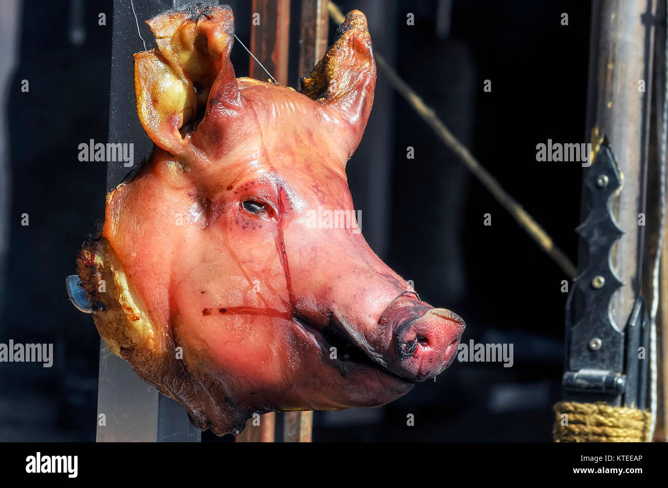 Head of pig. Rest of blood over the face. Barbecue stall in Medieval market. Slaughter of a pig. Sunny day. Cooking at outdoor. Traditions foods Stock Photo