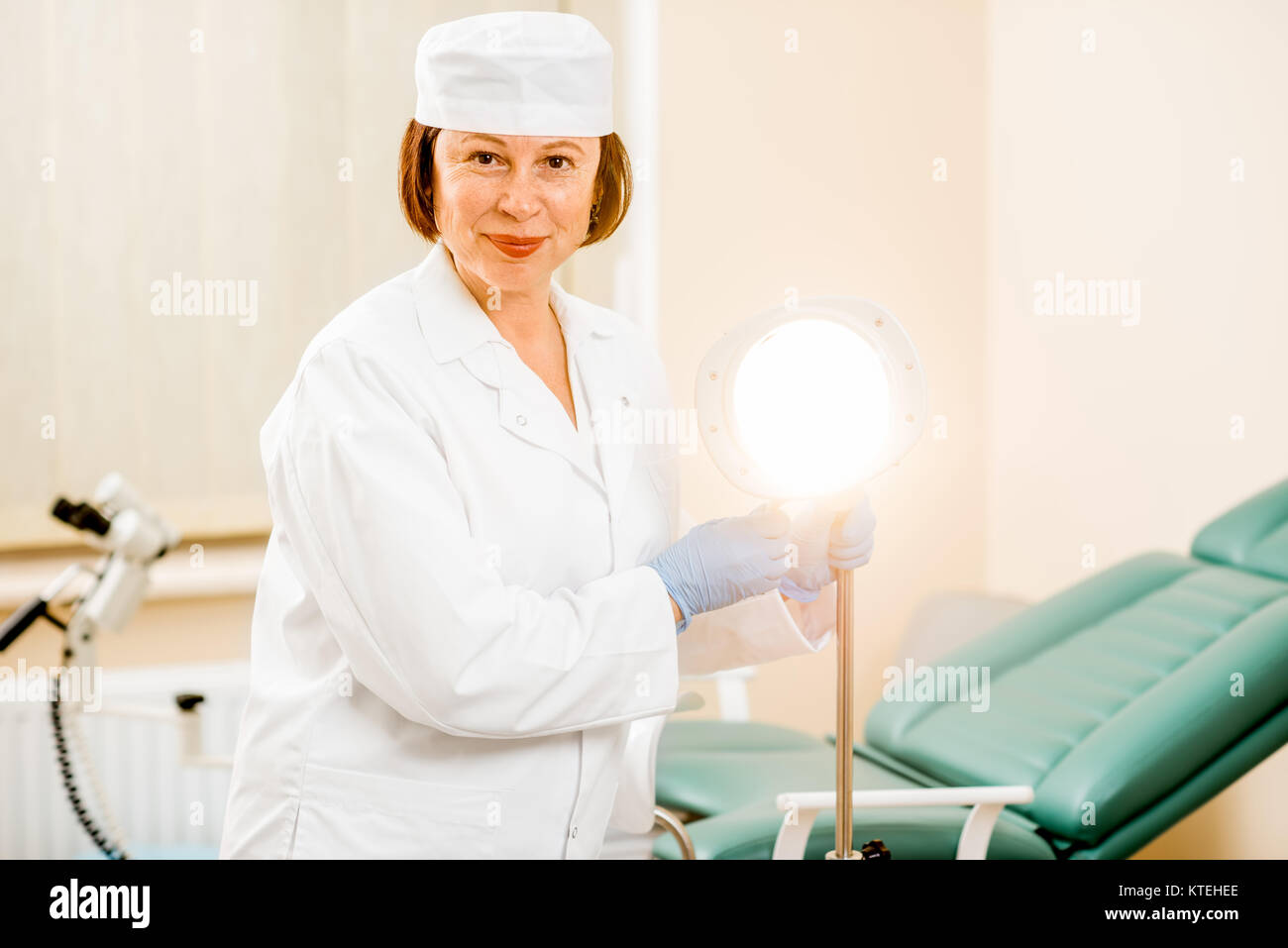 Portrait of a senior woman gynecologist in medical gown and hat preparing for procedure in the gynecological office Stock Photo