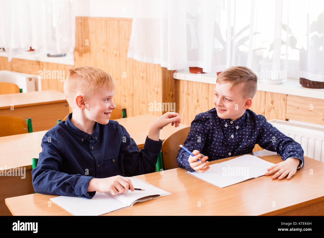 Boy white in the copybook during the lesson of primary school. Two boys are  talking and don't listening the teacher Stock Photo - Alamy