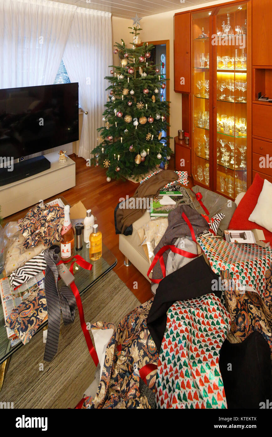 Christmas,Advent season,festive decorated Christmas tree in a living room,Christmas glitter balls,Christmas stars,unpacked Christmas gifts and gift wrapping paper after handing out of presents all in a tumble,confusion,confused,chaotic,consumption,pressures of a materialistic society Stock Photo