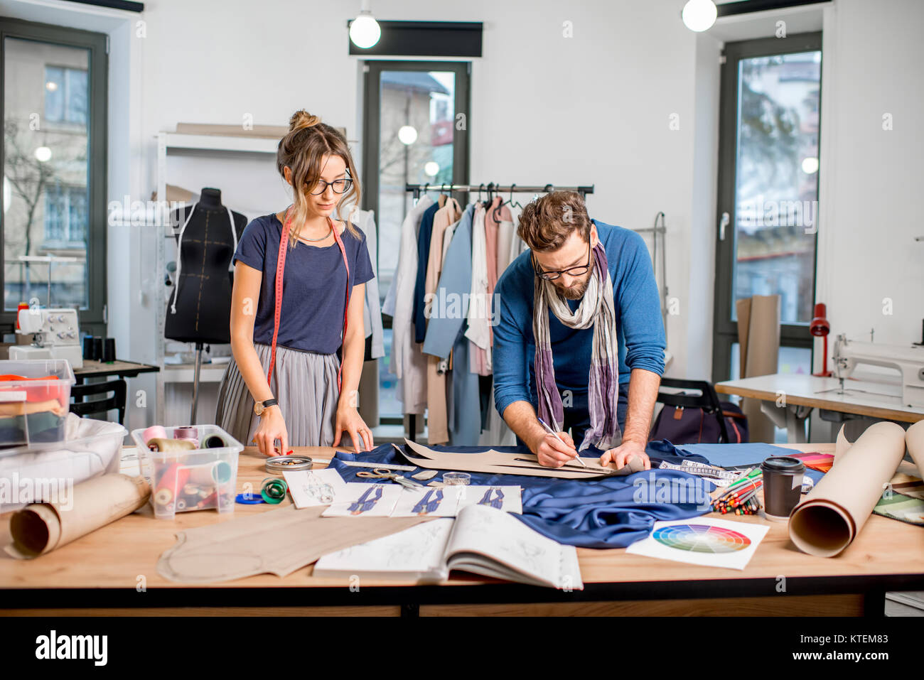 Couple of fashion designers working with fabric at the studio full of