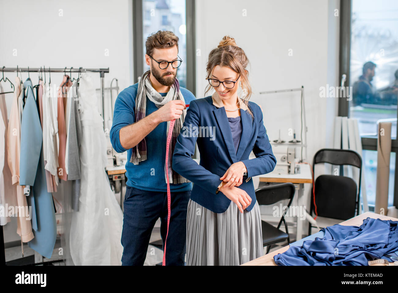 https://c8.alamy.com/comp/KTEMAD/handsome-tailor-measuring-jacket-on-the-woman-client-standing-at-the-KTEMAD.jpg