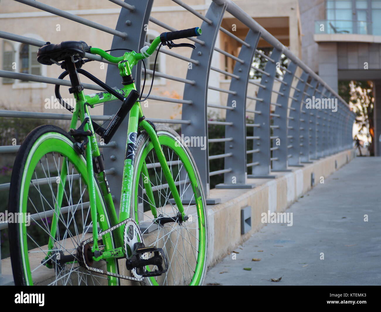 greenish city single speed bike parking on bridge u locked to banister Stock Photo