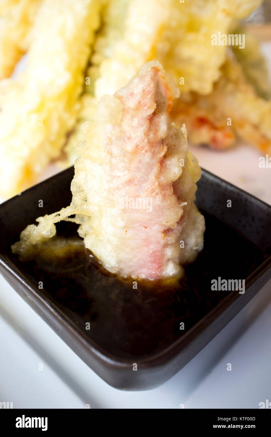 Dipping vegetable tempura in soya sauce bowl. Closeup Stock Photo