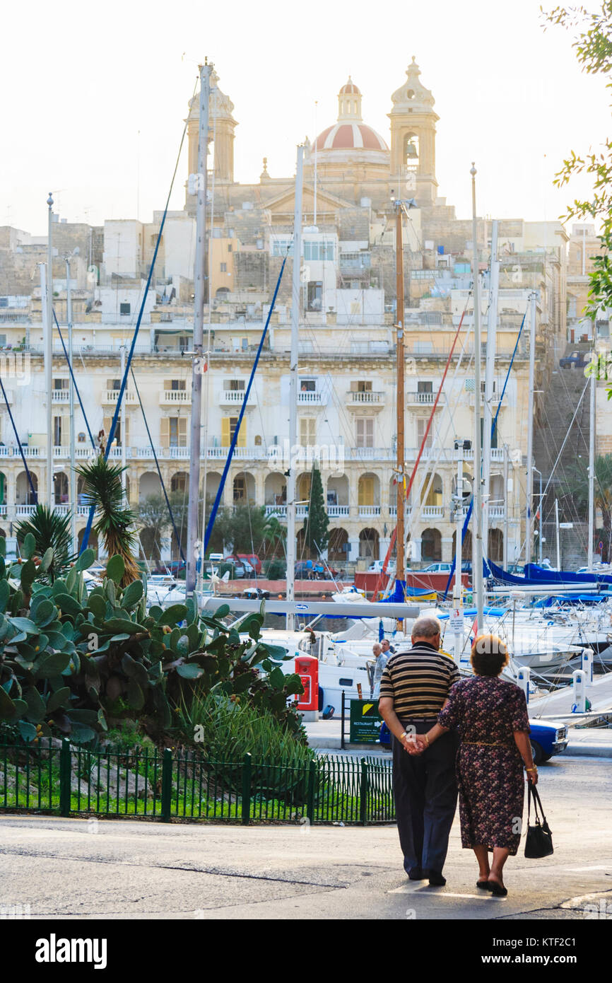 Elderly couple facing the marina and Senglea waterfront as seen from Birgu-Vittoriosa. Three cities, Grand Harbour, Malta Stock Photo