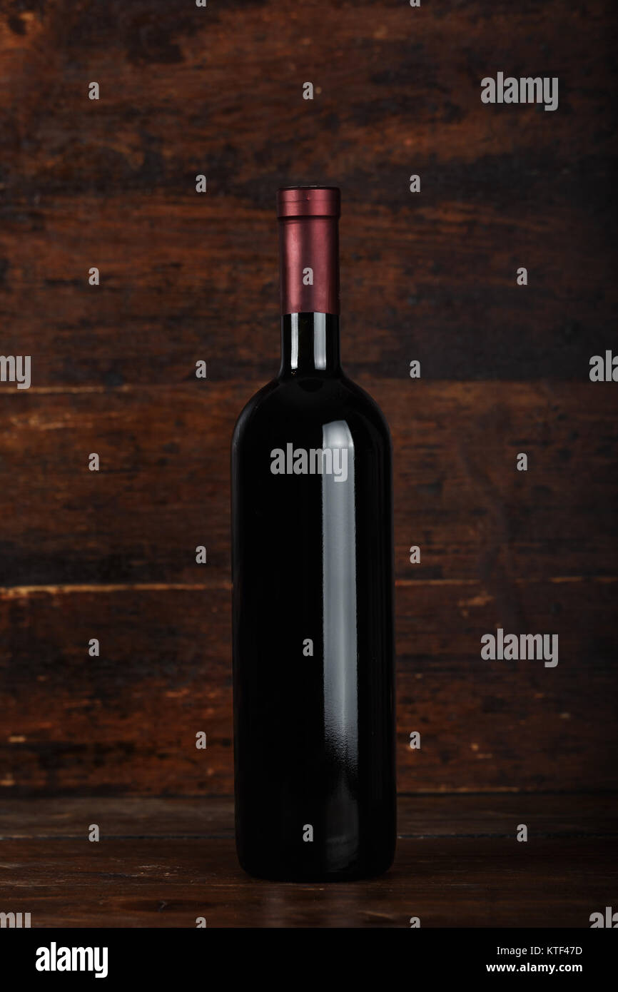 closed bottle of red wine on a wooden background, space for text Stock Photo