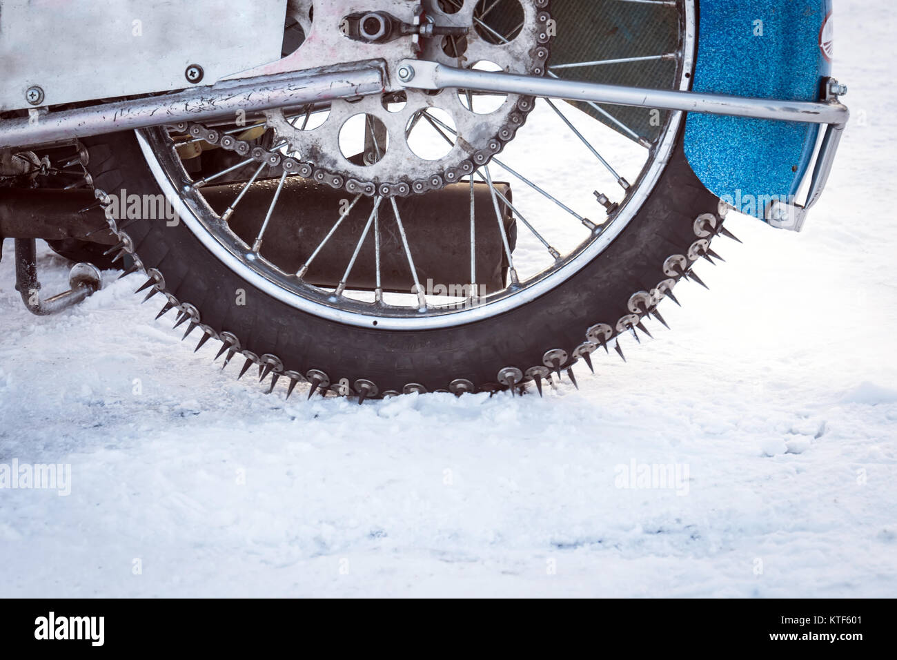 Tyre of motocross bike on ice and snow on background, selective focus on the middle part. special winter tire with studs for riding on ice. winter Spe Stock Photo