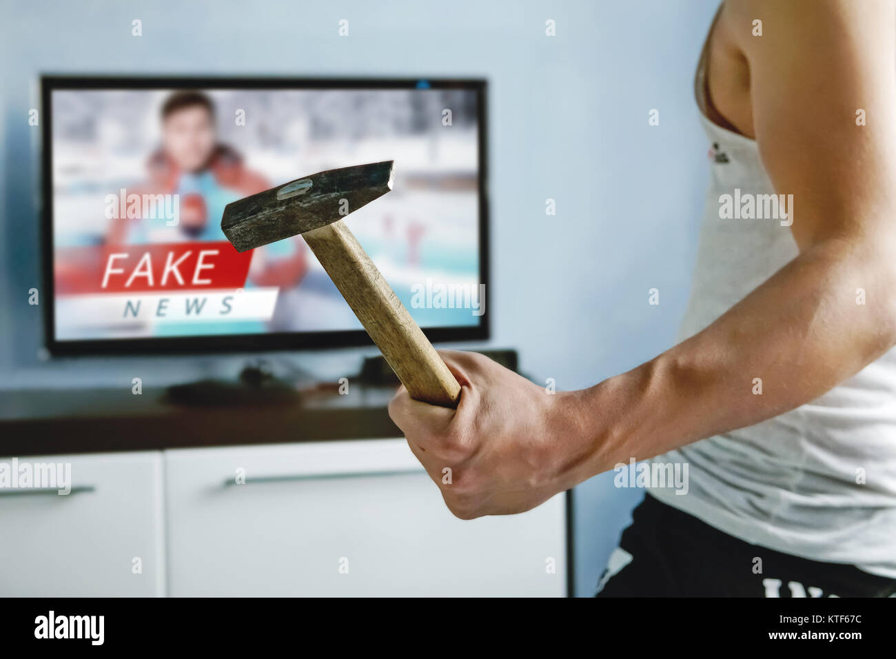 A psychopath wants to crash the TV with a hammer. The viewers got tired of  false news. Truth misrepresented in the news on a modern TV. fake news repo  Stock Photo -