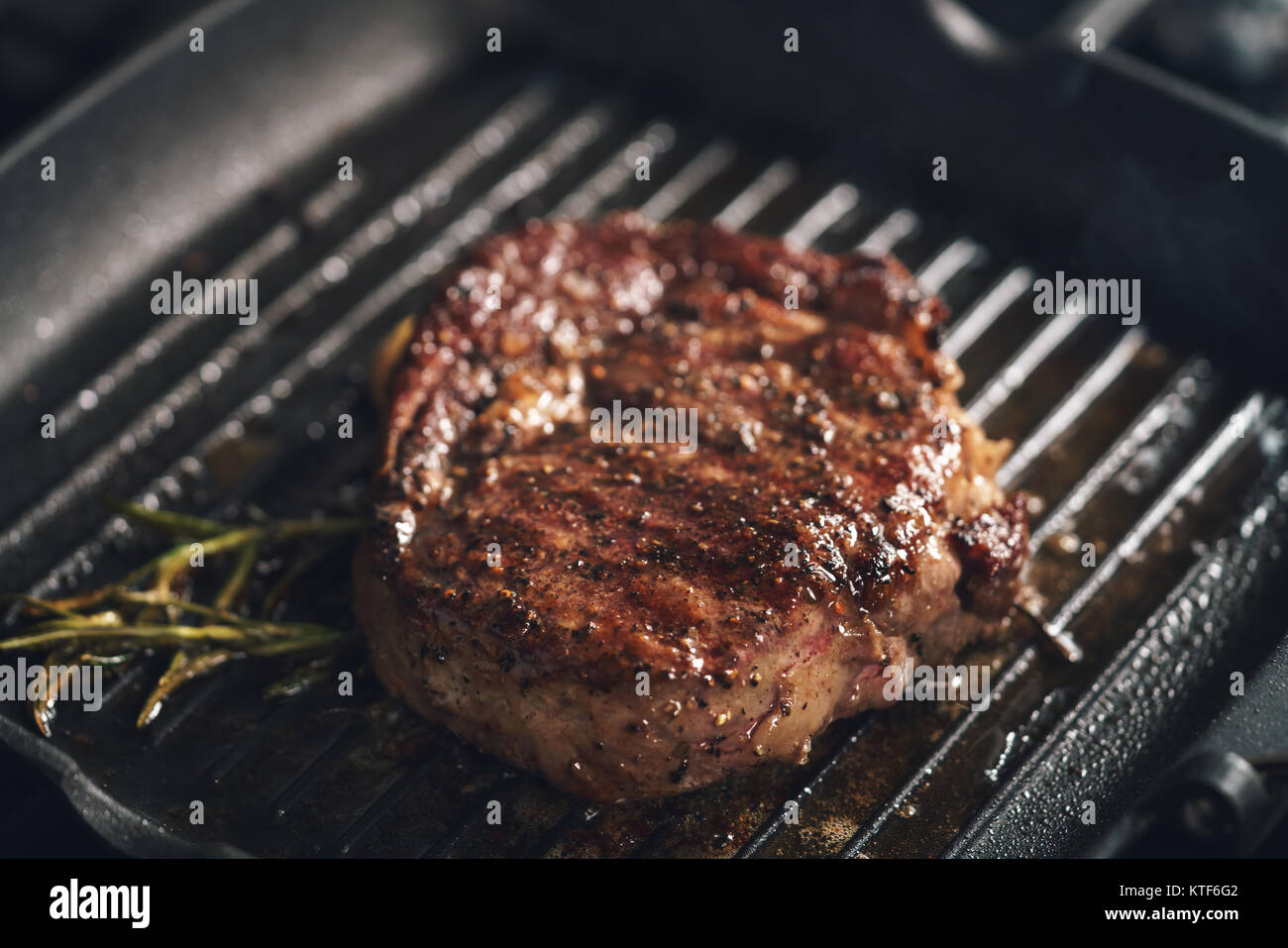 cooking rib eye steak with herbs on grill pan Stock Photo Alamy