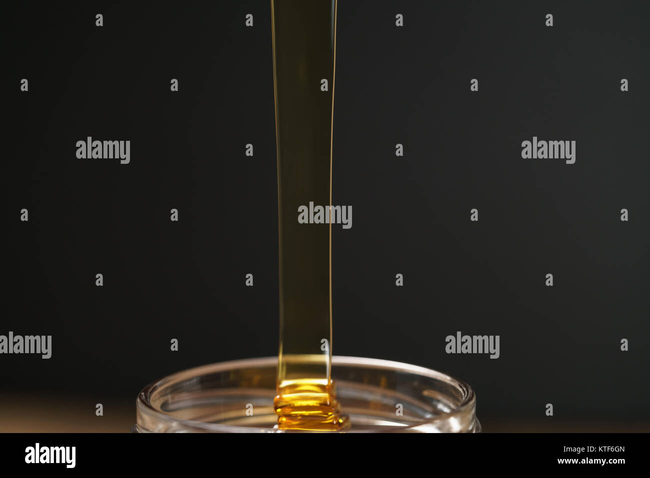 pour honey into glass jar closeup Stock Photo