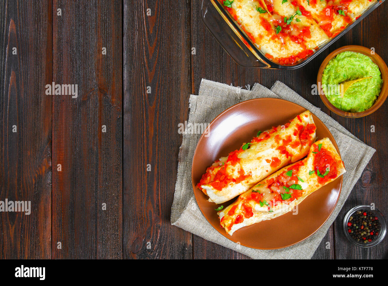 Homemade chicken enchiladas in dish on wooden table. Top view Stock Photo